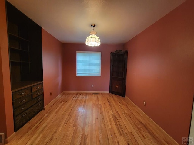 unfurnished dining area featuring light wood-type flooring and baseboards