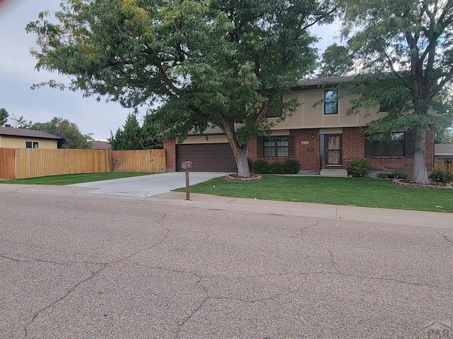 view of front facade with a garage, brick siding, concrete driveway, fence, and a front yard