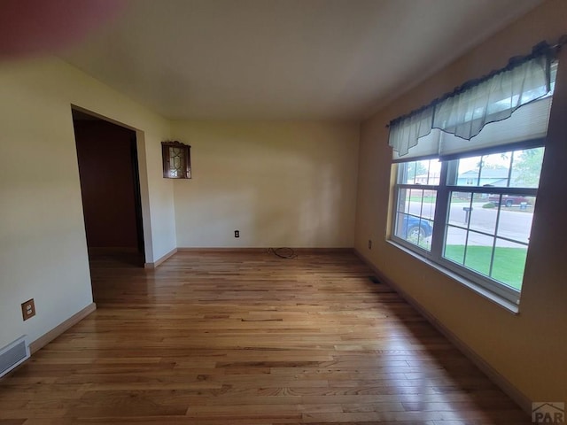 empty room with visible vents, baseboards, and wood finished floors