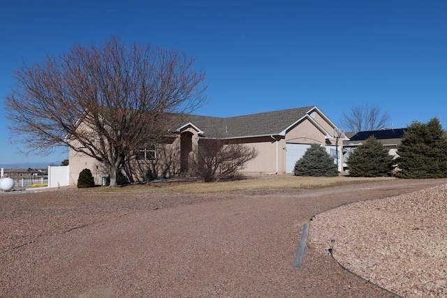 ranch-style home featuring a garage, driveway, fence, and stucco siding