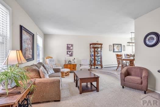 living area featuring a baseboard radiator, light colored carpet, and baseboards