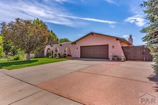 view of front of home with a garage, fence, driveway, stucco siding, and a front yard