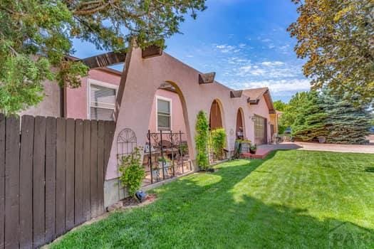 view of side of property featuring a yard, stucco siding, an attached garage, fence, and driveway