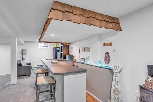 kitchen with a peninsula, dark countertops, a kitchen bar, and open floor plan