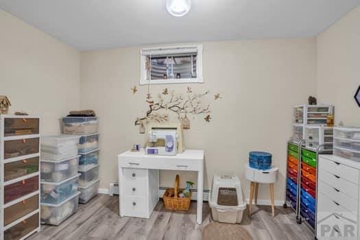 office space featuring light wood-style floors, a baseboard radiator, and baseboards