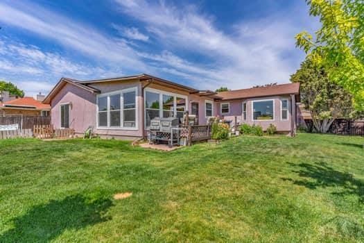 rear view of property with fence and a lawn