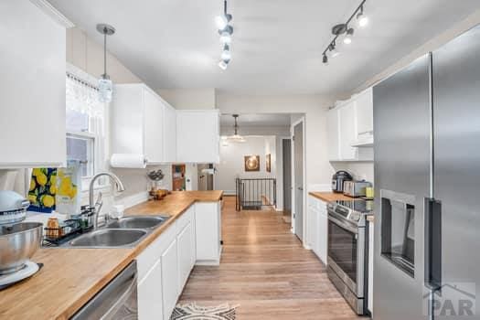 kitchen featuring decorative light fixtures, stainless steel appliances, light countertops, white cabinetry, and a sink