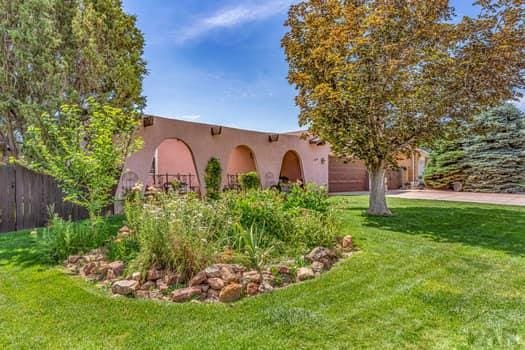 southwest-style home featuring a garage, a front yard, fence, and stucco siding