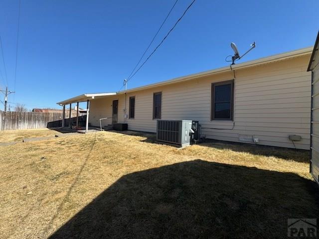 back of house with a lawn, central AC unit, and fence