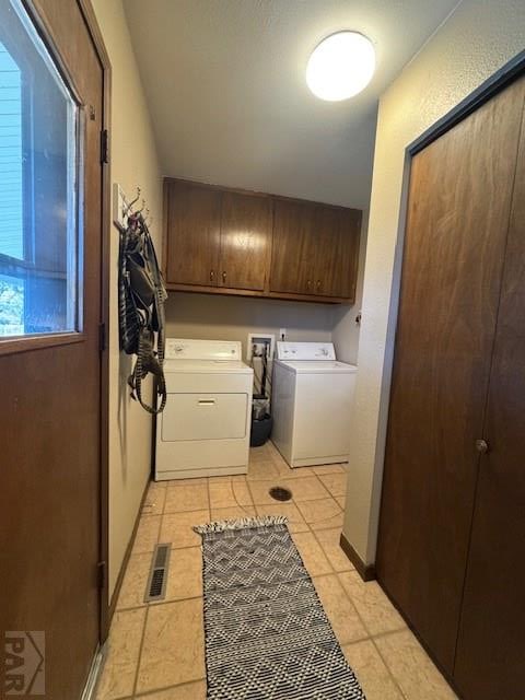 clothes washing area with light tile patterned floors, cabinet space, separate washer and dryer, and visible vents
