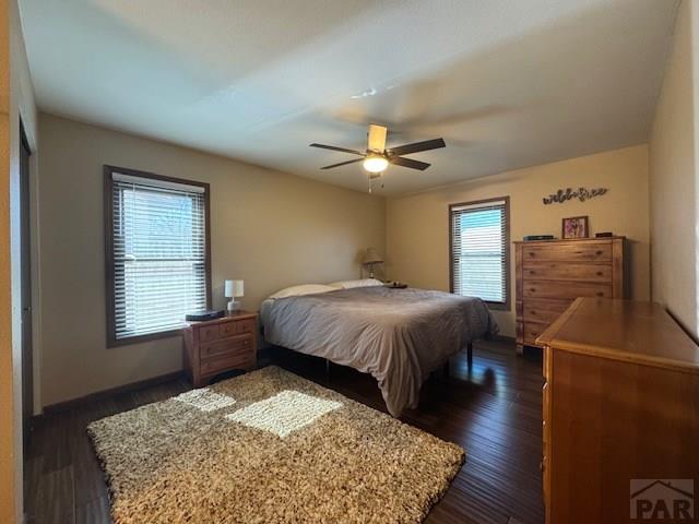 bedroom with dark wood finished floors, baseboards, and ceiling fan