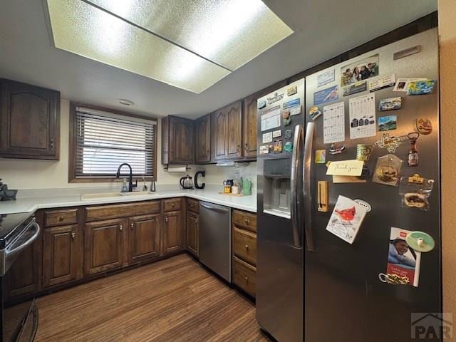 kitchen featuring a sink, light countertops, appliances with stainless steel finishes, and dark wood-type flooring