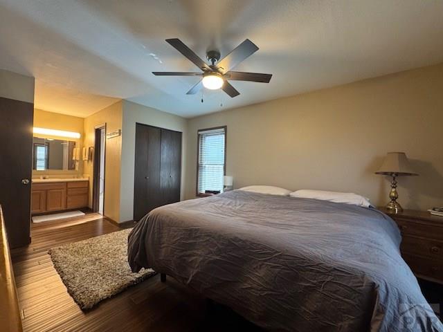 bedroom featuring a closet, connected bathroom, wood finished floors, and a ceiling fan