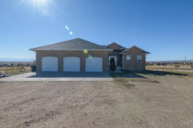 view of front of house featuring driveway, an attached garage, and a shingled roof