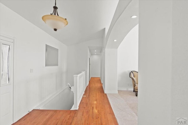 corridor featuring arched walkways, lofted ceiling, recessed lighting, light wood-style flooring, and baseboards