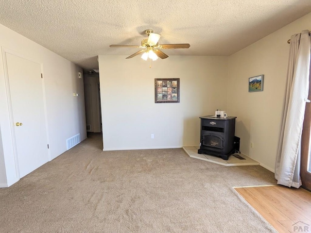 interior space with carpet floors, a wood stove, and a textured ceiling