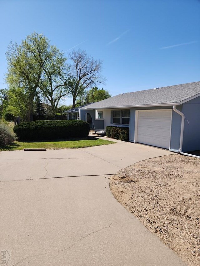 single story home featuring a front yard, driveway, a garage, and stucco siding