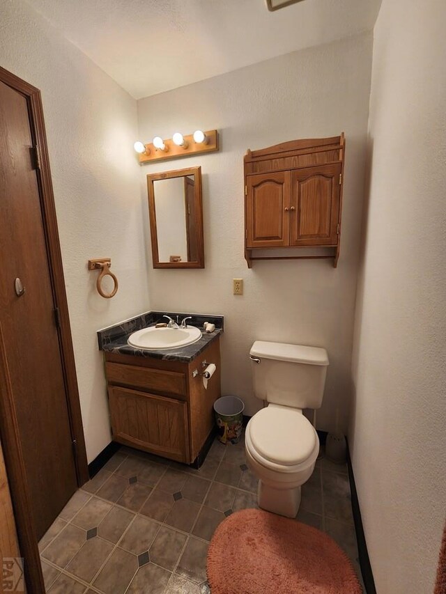 half bathroom with tile patterned floors, toilet, and vanity