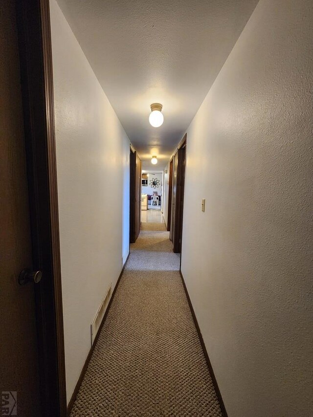 hallway with visible vents and light colored carpet