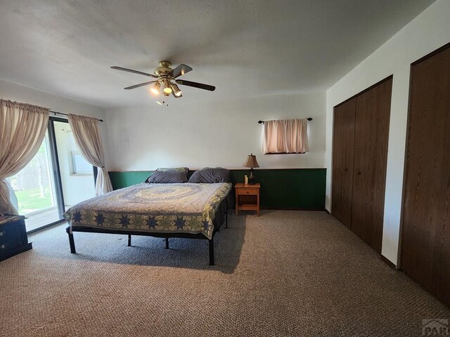 carpeted bedroom with two closets, a ceiling fan, and access to exterior
