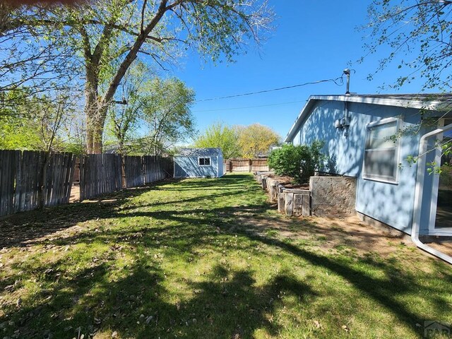 view of yard with a storage unit, an outdoor structure, and a fenced backyard