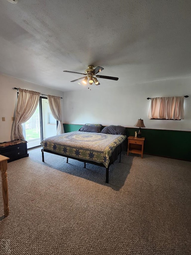 carpeted bedroom with access to exterior, a ceiling fan, and a textured ceiling