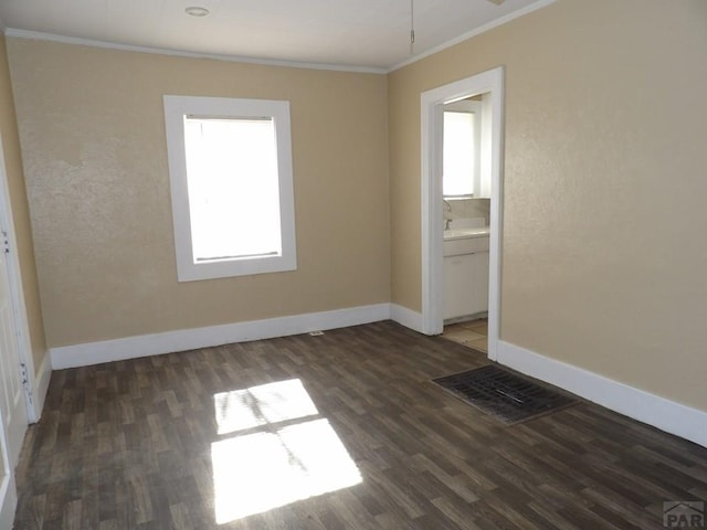 spare room with visible vents, baseboards, crown molding, and wood finished floors