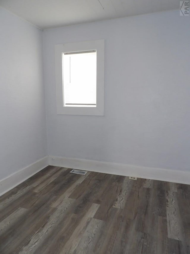 unfurnished room featuring baseboards, visible vents, and dark wood-style flooring