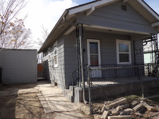 view of property exterior with a porch and an outbuilding