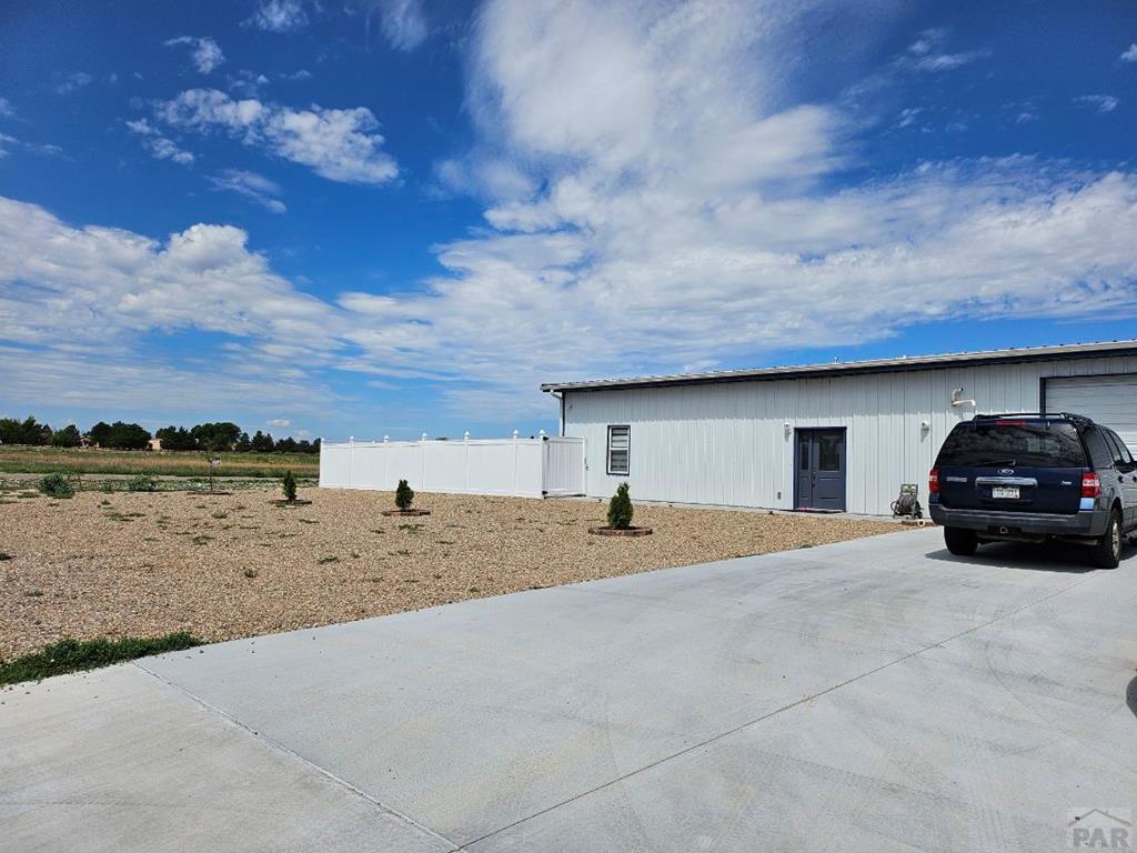 view of outdoor structure with a garage, concrete driveway, an outdoor structure, and fence