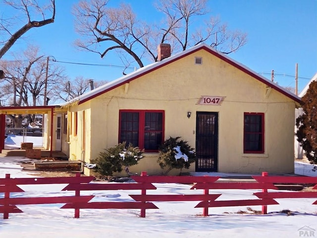 view of front of home with a fenced front yard, a chimney, and stucco siding