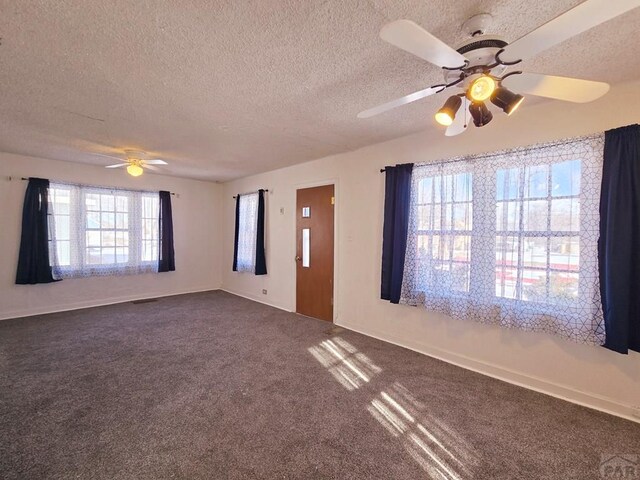 unfurnished room featuring a textured ceiling, dark colored carpet, visible vents, and a ceiling fan