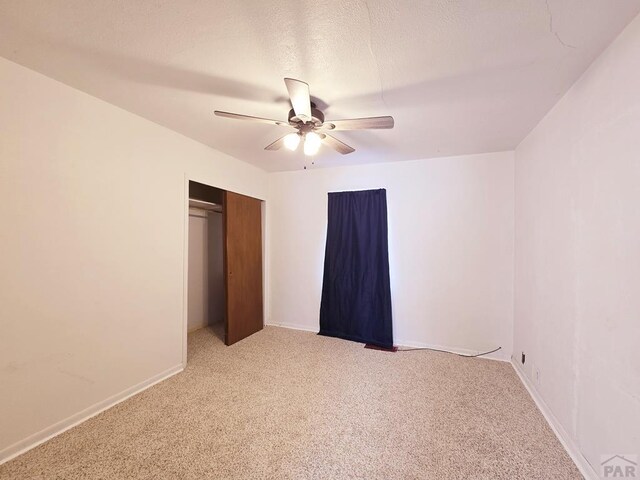 unfurnished bedroom featuring a closet, light carpet, ceiling fan, and baseboards