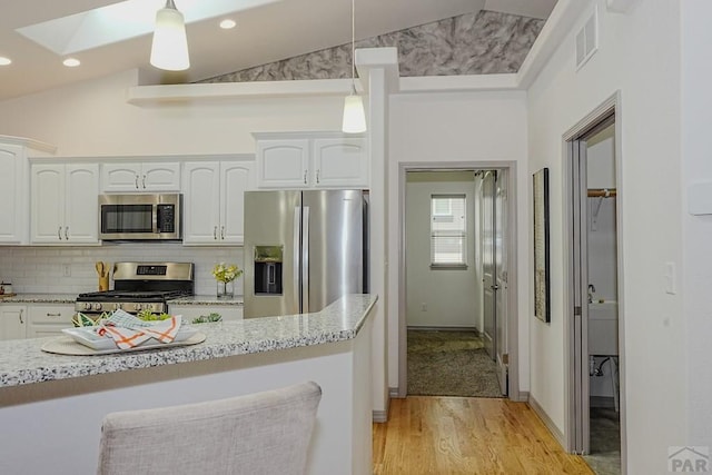 2221 Cliffmoor Ln, Pueblo, CO 81008 - kitchen with appliances with stainless steel finishes, white cabinets, vaulted ceiling, light wood-style flooring, and hanging light fixtures