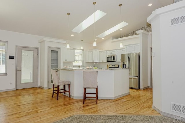 2221 Cliffmoor Ln, Pueblo, CO 81008 - kitchen with appliances with stainless steel finishes, a skylight, plenty of natural light, white cabinetry, and lofted ceiling