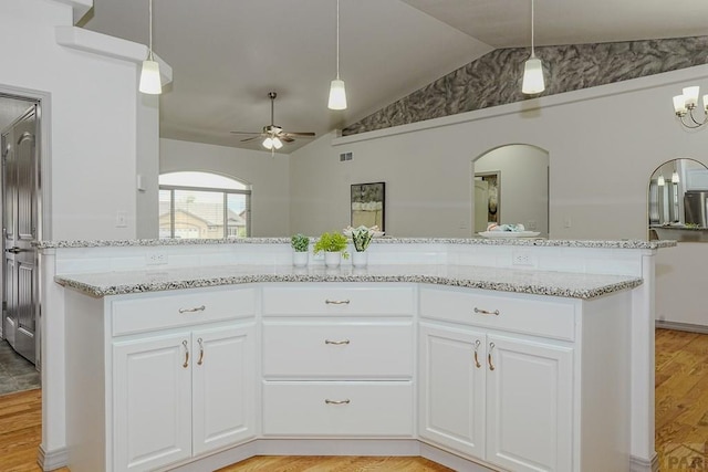 2221 Cliffmoor Ln, Pueblo, CO 81008 - kitchen with vaulted ceiling, light stone countertops, ceiling fan, white cabinets, and arched walkways