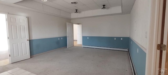 empty room featuring a baseboard radiator, visible vents, and a tray ceiling