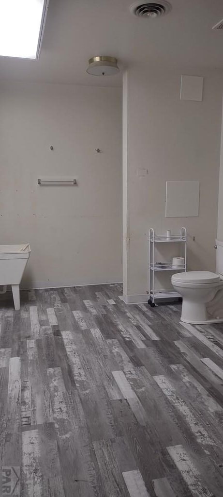 bathroom with toilet, visible vents, and wood finished floors