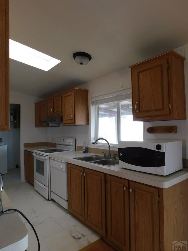 kitchen featuring marble finish floor, brown cabinets, light countertops, a sink, and white appliances