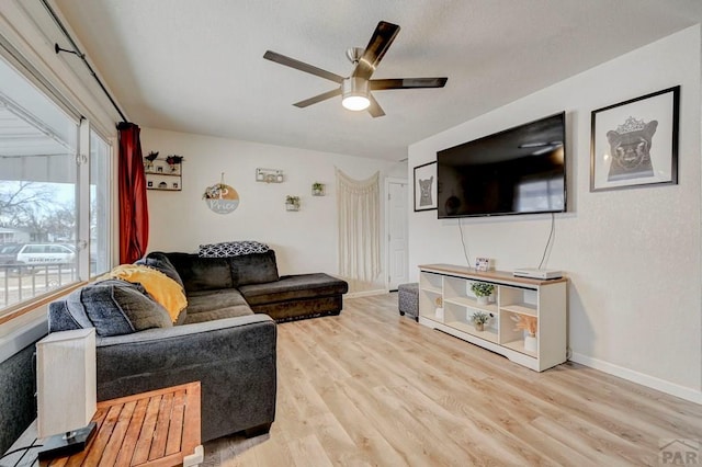 living room with ceiling fan, baseboards, and wood finished floors