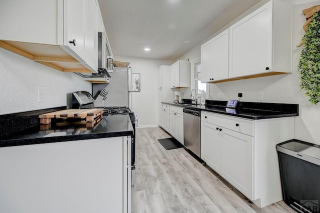 kitchen featuring stainless steel appliances, light wood-style flooring, a sink, and white cabinetry