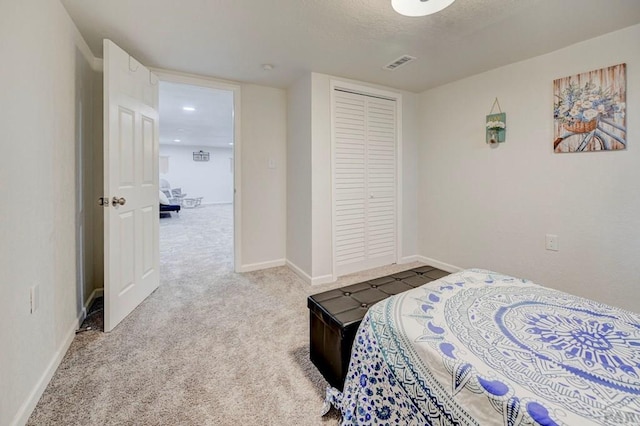 carpeted bedroom featuring a closet, visible vents, a textured ceiling, and baseboards