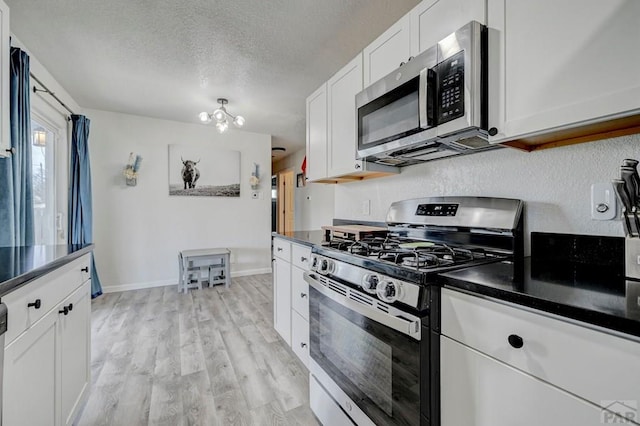 kitchen with stainless steel appliances, dark countertops, light wood-type flooring, and a textured ceiling