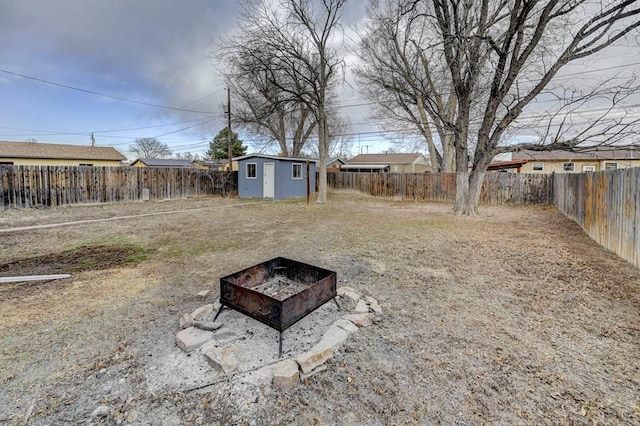 view of yard featuring a fenced backyard, an outdoor structure, a fire pit, and a storage shed