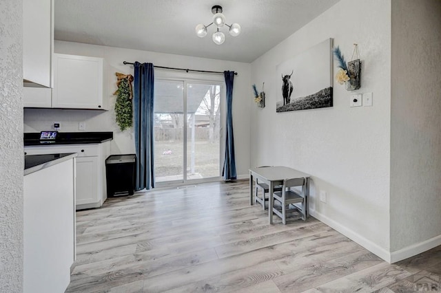 dining room featuring baseboards, an inviting chandelier, and light wood-style floors