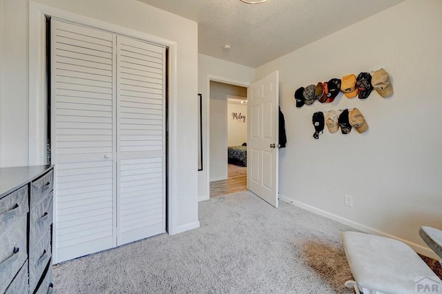 carpeted bedroom featuring a closet, a textured ceiling, and baseboards