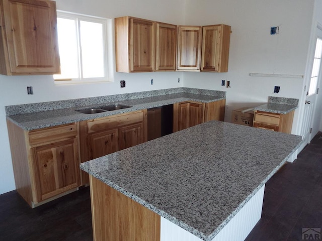 kitchen featuring dishwasher, dark wood-type flooring, a kitchen island, and a sink