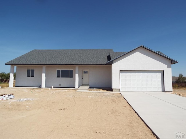 single story home with a garage, driveway, roof with shingles, and stucco siding