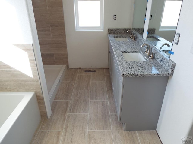 bathroom featuring double vanity, a sink, a bath, and wood tiled floor