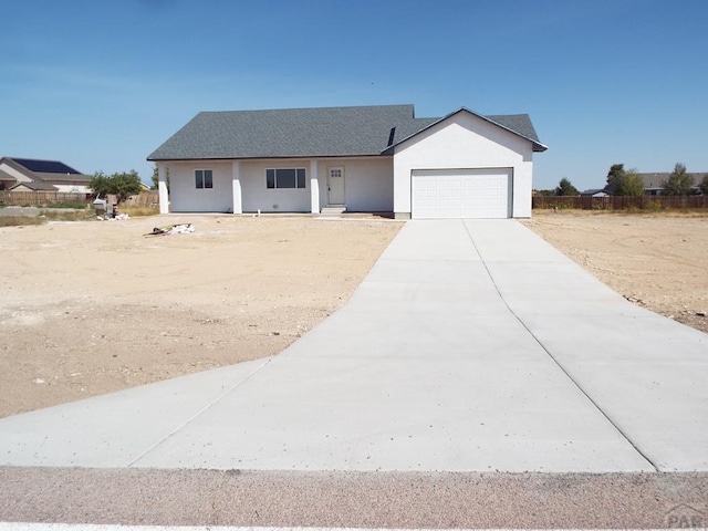 single story home with a garage, concrete driveway, and stucco siding